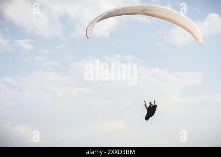 Il parapendio professionista in una tuta da cocco vola in alto sopra il suolo contro il cielo Foto Stock