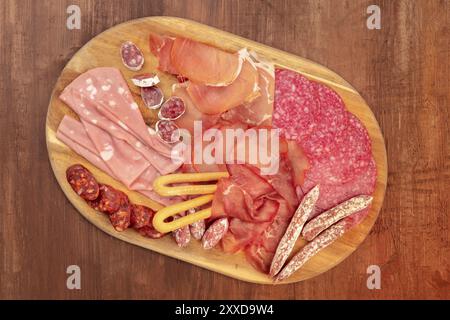 Degustazione di salumi. Una foto sovrastante di un vassoio con salsicce e prosciutti diversi, affettati, scattata dall'alto su uno sfondo rustico scuro con una Foto Stock