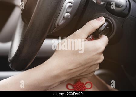 Primo piano interno veicolo di mano in possesso della chiave di accensione, il volante e il nero di fondo interna femmina, il concetto di driver Foto Stock