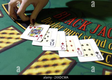 Mani di una donna croupier spacciatrice a un tavolo di carte di Blackjack che spacciano carte in un casinò Foto Stock