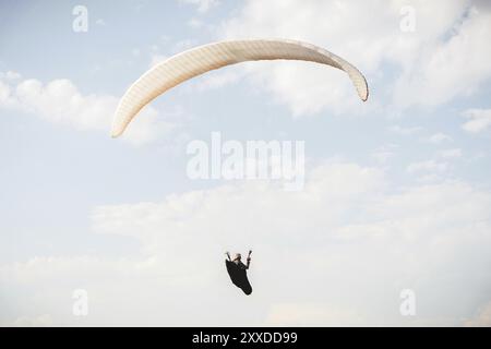 Il parapendio professionista in una tuta da cocco vola in alto sopra il suolo contro il cielo Foto Stock