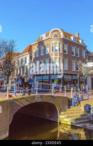 Delft, Paesi Bassi, 8 aprile 2016: Vista colorata sulla strada con tradizionali case olandesi, ponti, persone e canali Foto Stock