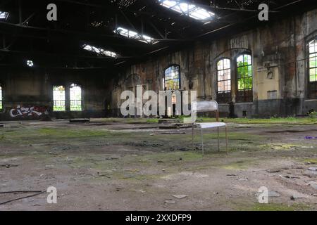 Una sedia si trova in un edificio di fabbrica in disuso Foto Stock