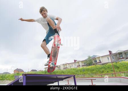 Giovane e intenso skateboarder in salto in alto contro il cielo e le zone notte Foto Stock