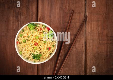 Una ciotola di Soba Noodles con verdure, girato da sopra al buio su un rustico sfondo di legno con bacchette e spazio di copia Foto Stock