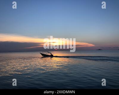 Barca che passa nelle isole Perhentiane durante il tramonto, Malesia Foto Stock