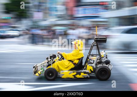 Un turista vestito come il famoso Pokemon Pikachu guida un go-kart per le strade di Shibuya a Tokyo. Shibuya Crossing. Foto Stock