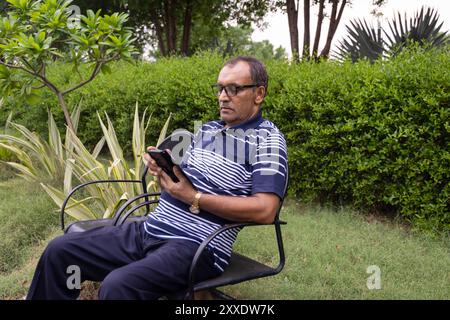 uomo isolato che usa il telefono cellulare in un parco all'aperto la sera da diverse angolazioni Foto Stock