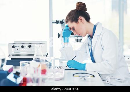 Stanca, donna o scienziata che scrive in laboratorio con studi scientifici per la ricerca per testare sperimentare sperimentare con scadenza o stress. Mal di testa, fisico esausto o. Foto Stock