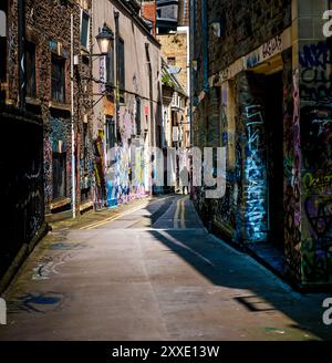 Persona che cammina lungo Lenard Lane Bristol, arte di strada, pareti coperte di graffiti Foto Stock