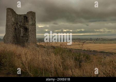 Castello di Hadleigh, Regno Unito. 24 agosto 2024. Una torre di pietra intemprata si erge da sola in cima a una collina erbosa, che si affaccia su un vasto paesaggio rurale sotto un cielo mostruoso e coperto. La struttura, forse un residuo di una fortificazione medievale o di un castello, evoca temi di solitudine, storia e il passare del tempo. Un inizio bagnato e cupo per il fine settimana festivo al Castello di Hadleigh, affacciato sull'estuario del Tamigi. Penelope Barritt/Alamy Live News Foto Stock
