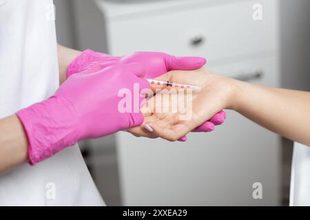 Il medico cosmetologo fa iniezioni di tossina botulinica sui palmi di una donna contro iperidrosi. Cosmetologia femminile, cura della pelle. Foto Stock