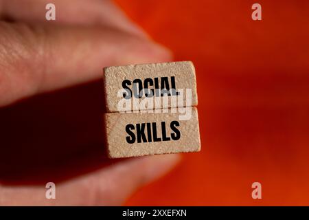 Messaggio di abilità sociali scritto su blocchi di legno con sfondo arancione. Simbolo delle capacità sociali concettuali. Copia spazio. Foto Stock