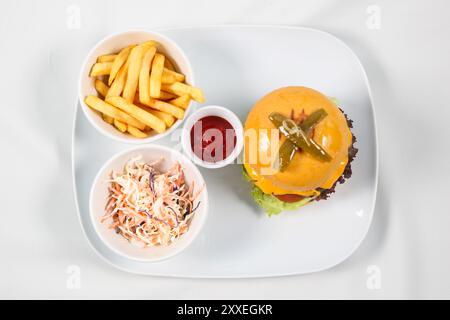 Hamburger al formaggio, manzo, pancetta, cipolla, formaggio, lattuga e pomodoro a fette servito con patatine fritte e maionese, isolato su sfondo bianco Foto Stock