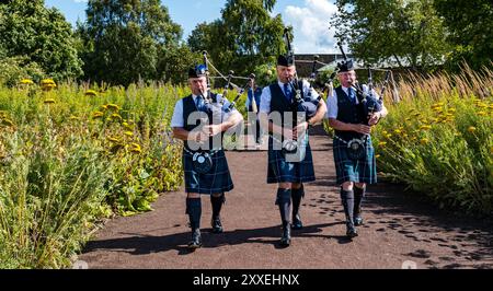 Giardino recintato di Amisfield, Haddington, East Lothian, Scozia, Regno Unito. Scotland's Gardens Scheme Free Gardeners: Un grande giardino murato del XVIII secolo segna la storia dell'ordine dei giardinieri liberi, una società fraterna fondata nel XVII secolo. La prova più antica è la loggia di Haddington aperta nel 1676. I primi membri della loggia erano piccoli proprietari terrieri e agricoltori che praticavano il giardinaggio per piacere, come un primo sindacato. Nella foto: Un pifferaio Haddington Pipe Band sfilano intorno al giardino con volontari che trasportano un boccaglio di fiori. Crediti: Sally Anderson/Alamy Live News Foto Stock