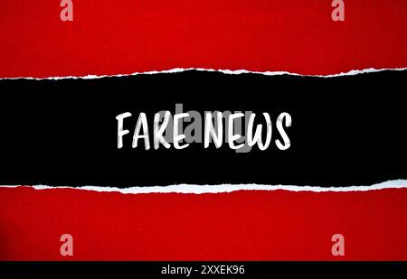 Falso messaggio scritto su carta rossa strappata con sfondo nero. Simbolo di notizie false concettuali. Copia spazio. Foto Stock