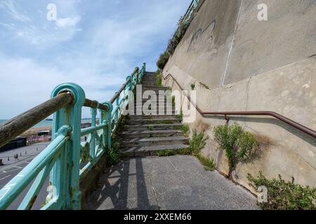 Scale che conducono al muro della scogliera Est il muro su Madeira Drive ha la prima targa verde del paese a segnare il muro Verde 150esimo anno. Foto Stock