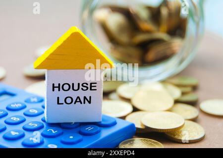 Testo del prestito della casa sulla casa dei giocattoli in legno con calcolatrice e sfondo delle monete d'oro. Concetto di mutuo e mutuo. Foto Stock