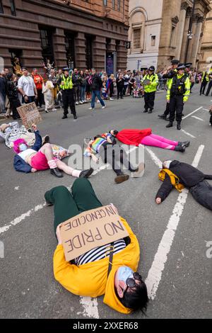 Manchester, Regno Unito. 24 agosto 2024. Palestina dimostranti di guerra di Gaza che si trovano sulla strada prima della Pride Parade. I manifestanti palestinesi non sono riusciti a impedire che la Pride Parade si svolgesse dopo aver bloccato la strada su Peter Street posando sulla strada. Si opponevano contro Booking.com che portavano anche pubblicità per proprietà in Israele. La polizia si è mossa e ha ripulito la protesta permettendo alla protesta di procedere. Alcuni individui nella parata dove trasportavano bandiere palestinesi. Manchester Pride 2024 . Il tema di quest'anno è "Buzzin to be Queer - A Hive of Progress". Il simbolo del Manchester Bee ha guidato la parata. Credito Foto Stock