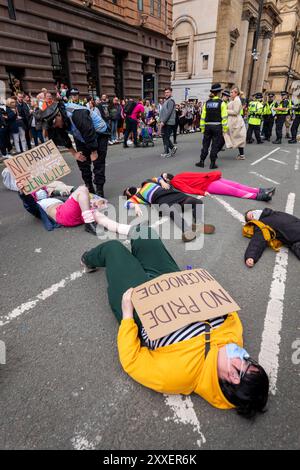 Manchester, Regno Unito. 24 agosto 2024. Palestina dimostranti di guerra di Gaza che si trovano sulla strada prima della Pride Parade. I manifestanti palestinesi non sono riusciti a impedire che la Pride Parade si svolgesse dopo aver bloccato la strada su Peter Street posando sulla strada. Si opponevano contro Booking.com che portavano anche pubblicità per proprietà in Israele. La polizia si è mossa e ha ripulito la protesta permettendo alla protesta di procedere. Alcuni individui nella parata dove trasportavano bandiere palestinesi. Manchester Pride 2024 . Il tema di quest'anno è "Buzzin to be Queer - A Hive of Progress". Il simbolo del Manchester Bee ha guidato la parata. Credito Foto Stock