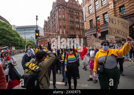 Manchester, UK. 24th Aug, 2024. Palestine war protesters are cleared by police on Peters Street ahead of Manchester Pride parade.Palestinian protesters failed to prevent Pride Parade taking place after they blocked road on Peter Street by laying in road. They were objecting against Booking.com who also carry adverts for properties in Israel. The police moved in and cleared the protest allowing the protest to proceed. Some individuals in the parade where carrying Palestinian flags.Manchester Pride 2024 . This year's theme is 'Buzzin To Be Queer - A Hive of Progress' . The symbol of the Manchest Stock Photo