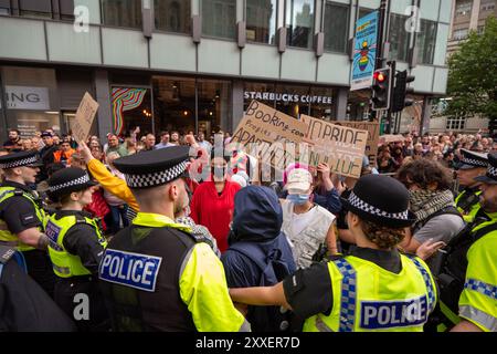 Manchester, UK. 24th Aug, 2024. Palestine war protesters are cleared by police on Peters Street ahead of Manchester Pride parade.Palestinian protesters failed to prevent Pride Parade taking place after they blocked road on Peter Street by laying in road. They were objecting against Booking.com who also carry adverts for properties in Israel. The police moved in and cleared the protest allowing the protest to proceed. Some individuals in the parade where carrying Palestinian flags.Manchester Pride 2024 . This year's theme is 'Buzzin To Be Queer - A Hive of Progress' . The symbol of the Manchest Stock Photo