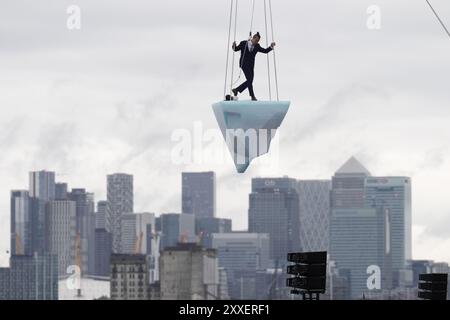 La prima europea di performance art THAW, uno spettacolo aereo di 8 ore si è esibito su 2,5 tonnellate di ghiaccio durante il Greenwich and Docklands International Festival nell'est di Londra. Creato dalla compagnia teatrale australiana LEGS ON THE WALL in risposta ai devastanti incendi boschivi del 2019/20, THAW porta i londinesi faccia a faccia con l'urgente necessità di un'azione globale per il clima. Questa produzione aerea è stata eseguita su un blocco di ghiaccio di 2,5 tonnellate che aumenta la potenza e l'urgenza mentre il ghiaccio, sospeso su una gru in alto sopra un iconico paesaggio docklands, si scioglie gradualmente. Data foto: Sabato agosto Foto Stock