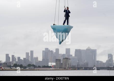 La prima europea di performance art THAW, uno spettacolo aereo di 8 ore si è esibito su 2,5 tonnellate di ghiaccio durante il Greenwich and Docklands International Festival nell'est di Londra. Creato dalla compagnia teatrale australiana LEGS ON THE WALL in risposta ai devastanti incendi boschivi del 2019/20, THAW porta i londinesi faccia a faccia con l'urgente necessità di un'azione globale per il clima. Questa produzione aerea è stata eseguita su un blocco di ghiaccio di 2,5 tonnellate che aumenta la potenza e l'urgenza mentre il ghiaccio, sospeso su una gru in alto sopra un iconico paesaggio docklands, si scioglie gradualmente. Data foto: Sabato agosto Foto Stock