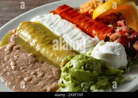 Una veduta di tre enchiladas ricoperte di salse, che rappresentano i colori della bandiera messicana. Foto Stock