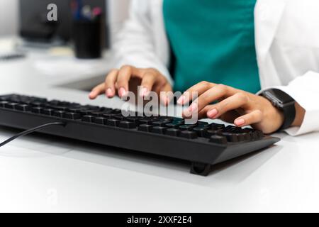 Primo piano delle mani di un medico che digita sulla tastiera Foto Stock