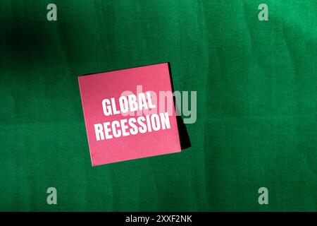 Messaggio di recessione globale scritto su carta rosa con sfondo verde. Simbolo di recessione globale concettuale. Copia spazio. Foto Stock