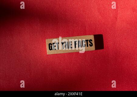 Ricevi il messaggio dei fatti scritto su un blocco di legno con sfondo rosso. Concettuale ottenere il simbolo dei fatti. Copia spazio. Foto Stock