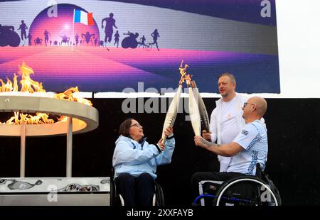 Stoke Mandeville, Gran Bretagna. 24 agosto 2024. Helene Raynsford (L) e Gregor Ewan (R) illuminano la torcia del presidente del Comitato paralimpico internazionale Andrew Parsons durante la cerimonia di accensione della torcia paralimpica per i Giochi paralimpici di Parigi 2024 a Stoke Mandeville, in Gran Bretagna, il 24 agosto 2024. Crediti: Li Ying/Xinhua/Alamy Live News Foto Stock