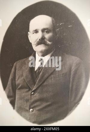 Ungheria, anni '1930: Ritratto in studio d'epoca di un signore anziano con baffi spessi sul manubrio, che indossa un completo formale in lana a tre pezzi con un gilet e una catena di orologi in argento visibile. Un classico esempio della moda borghese europea durante il periodo tra le due guerre. Foto Stock