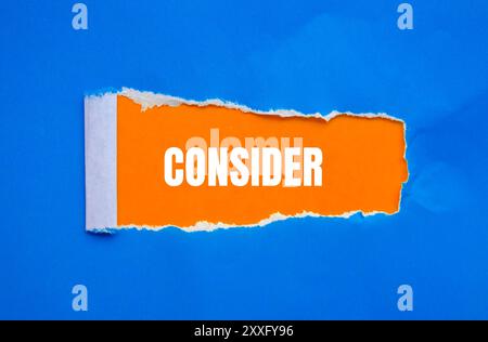 Considerare il messaggio scritto su carta strappata blu con sfondo arancione. Simbolo concettuale da considerare. Copia spazio. Foto Stock