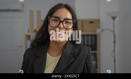 Donna sorridente in un ambiente d'ufficio, con un'atmosfera positiva e professionale e interni moderni e organizzati. Foto Stock