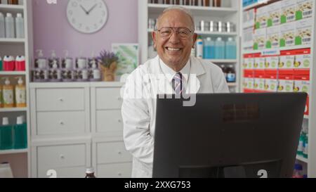 Uomo allegro che lavora in una farmacia, in piedi dietro il bancone con scaffali di farmaci e prodotti sullo sfondo. Foto Stock