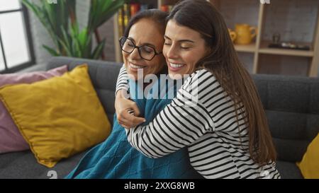 Una madre e una figlia affettuose che abbracciano in un accogliente soggiorno, irradiando amore e legame familiare. Foto Stock
