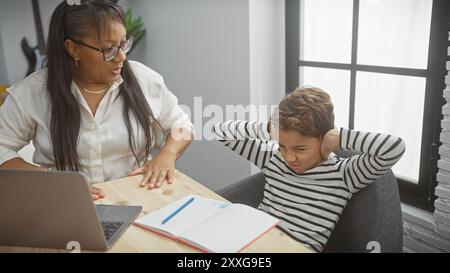 Una donna aiuta un ragazzo frustrato con i compiti in un salotto moderno Foto Stock