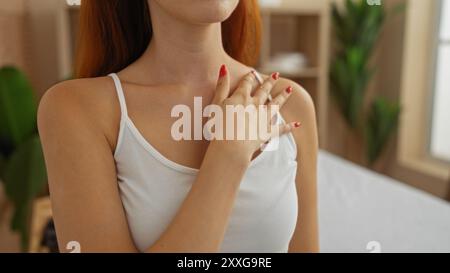 Giovane donna dai capelli rossi che si gode un momento di relax in un centro benessere o in una sala spa, con un ambiente interno sereno e tranquillo. Foto Stock