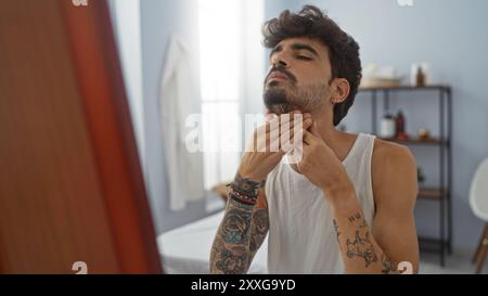 Bellissimo giovane ispanico con barba in un salone di benessere che esamina il suo viso nello specchio Foto Stock