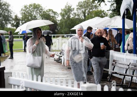 Windsor, Berkshire, Regno Unito. 24 agosto 2024. I Racegoers del Royal Windsor Racecourse non lasciarono che piogge intense e temporali rovinassero la loro serata al Summer Closing Party a Windsor, Berkshire. Crediti: Maureen McLean/Alamy Live News Foto Stock