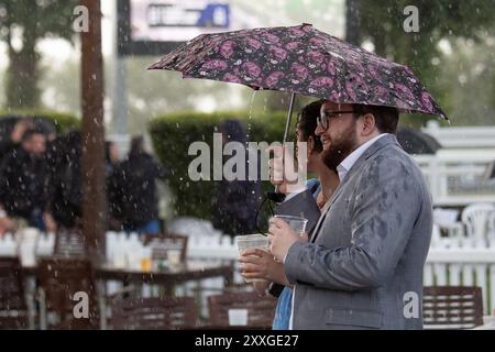 Windsor, Berkshire, Regno Unito. 24 agosto 2024. I Racegoers del Royal Windsor Racecourse non lasciarono che piogge intense e temporali rovinassero la loro serata al Summer Closing Party a Windsor, Berkshire. Crediti: Maureen McLean/Alamy Live News Foto Stock