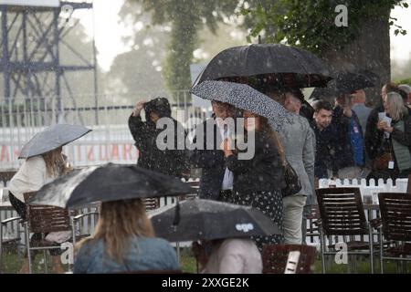 Windsor, Berkshire, Regno Unito. 24 agosto 2024. I Racegoers del Royal Windsor Racecourse non lasciarono che piogge intense e temporali rovinassero la loro serata al Summer Closing Party a Windsor, Berkshire. Crediti: Maureen McLean/Alamy Live News Foto Stock