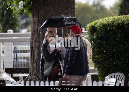 Windsor, Berkshire, UK. 24th August, 2024. Racegoers at Royal Windsor Racecourse didn't let heavy rain and thunderstorms spoil their evening at the Summer Closing Party in Windsor, Berkshire. Credit: Maureen McLean/Alamy Live News Stock Photo