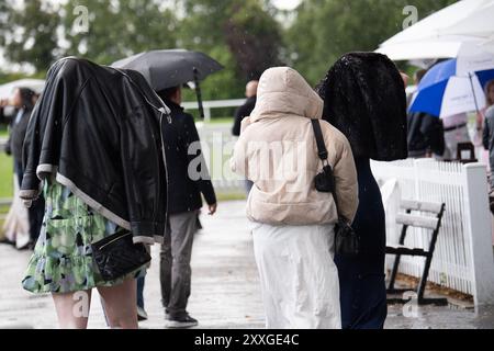 Windsor, Berkshire, Regno Unito. 24 agosto 2024. I Racegoers del Royal Windsor Racecourse non lasciarono che piogge intense e temporali rovinassero la loro serata al Summer Closing Party a Windsor, Berkshire. Crediti: Maureen McLean/Alamy Live News Foto Stock