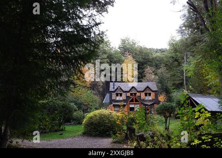 Un'accogliente cabina immersa in una foresta lussureggiante, circondata da un vivace fogliame autunnale Foto Stock