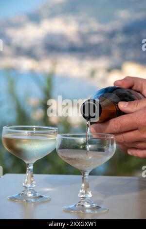 Spumante freddo, cava o champagne in due bicchieri da coupé sul tavolo con vista mare blu vicino a Mentone e Monte Carlo, Costa Azzurra, Francia Foto Stock