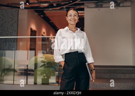 Una donna d'affari sicura di sé prospera in un ambiente moderno, che abbraccia la sua professionalità Foto Stock