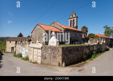 La chiesa Igrexa de San Xiao de Pedroso nel villaggio Eirexe lungo il Camino de Invierno in viaggio verso Santiago de Compostela. Inusuale per gli altri cimiteri di questa regione le nicchie di sepoltura si aprono sulla strada per mancanza di spazio. Foto Stock